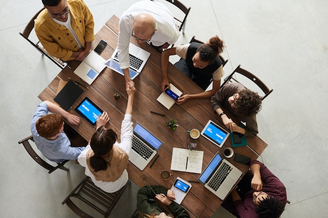 people around a table with laptops